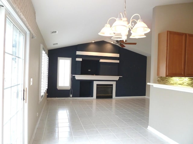 kitchen with a tiled fireplace, light tile patterned floors, lofted ceiling, and a healthy amount of sunlight