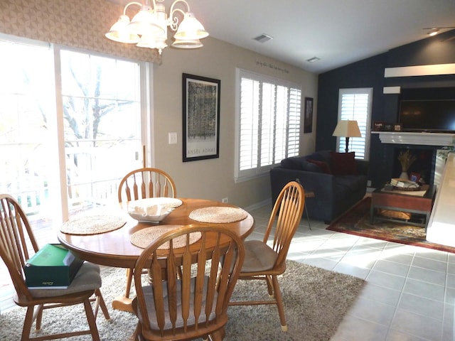 tiled dining space with vaulted ceiling and a chandelier