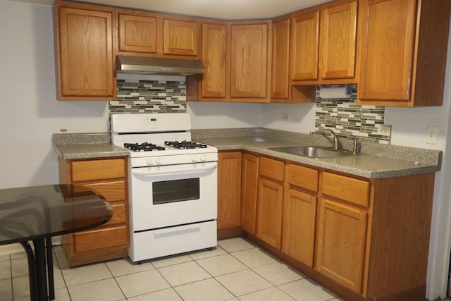 kitchen with under cabinet range hood, decorative backsplash, a sink, and gas range gas stove