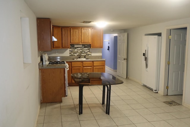 kitchen with white appliances, visible vents, a sink, brown cabinets, and baseboards
