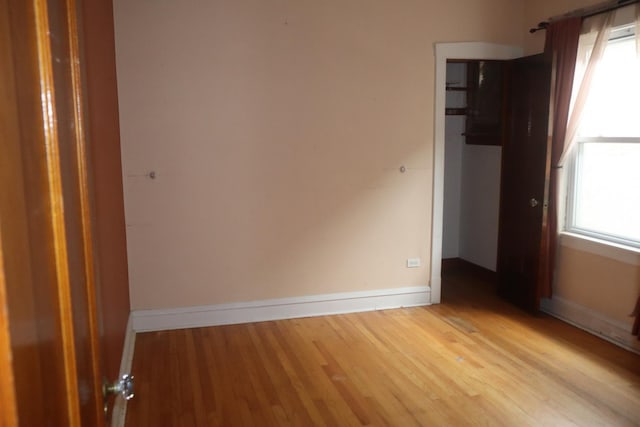 empty room featuring light wood-type flooring, a healthy amount of sunlight, and baseboards