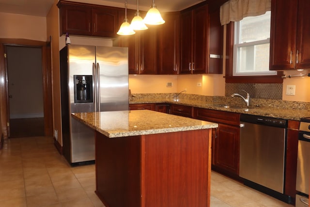 kitchen with light tile patterned floors, light stone countertops, appliances with stainless steel finishes, pendant lighting, and a sink