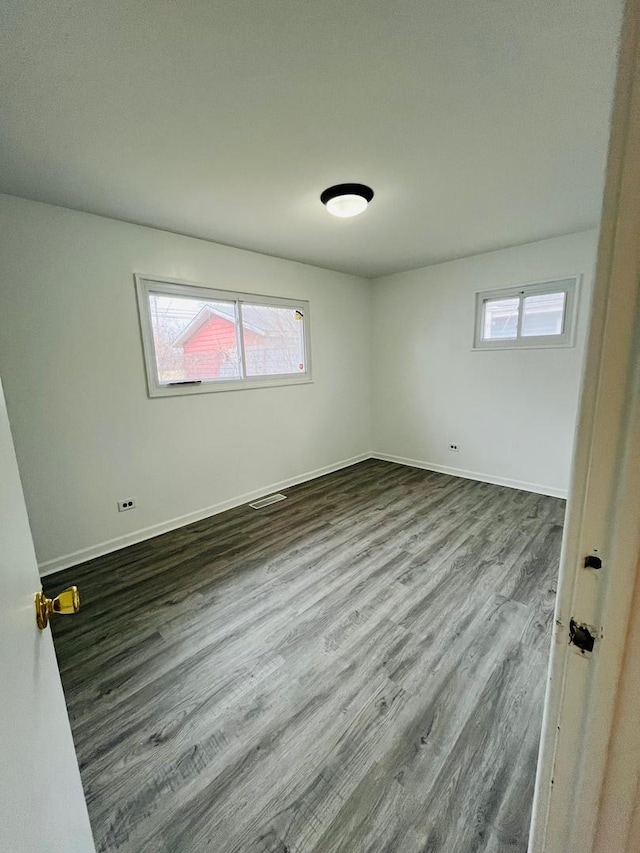 spare room featuring dark hardwood / wood-style floors and a healthy amount of sunlight