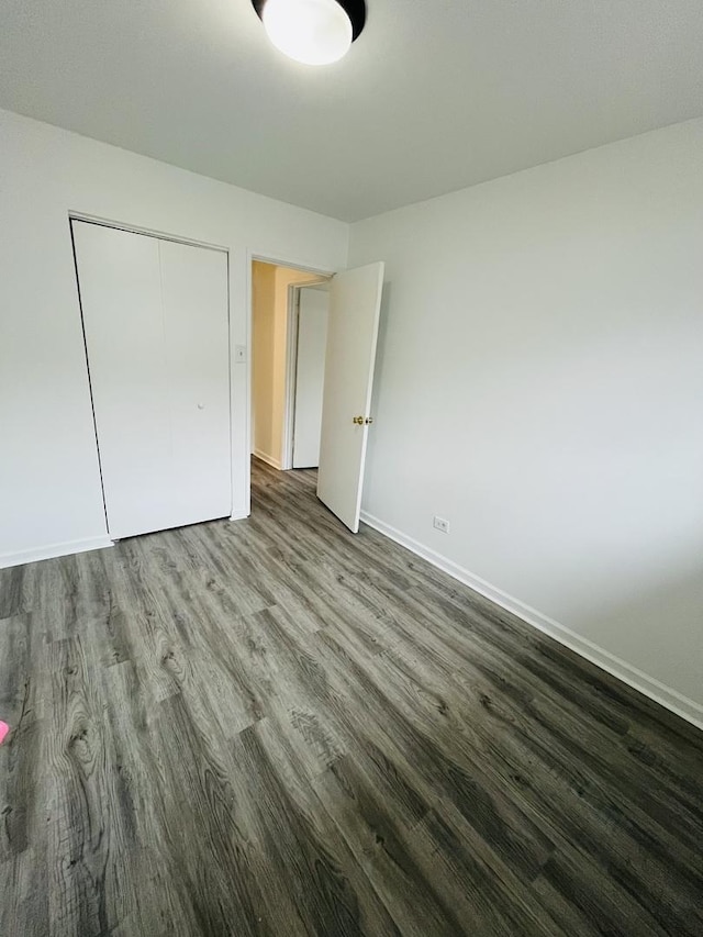 unfurnished bedroom featuring dark wood-type flooring and a closet