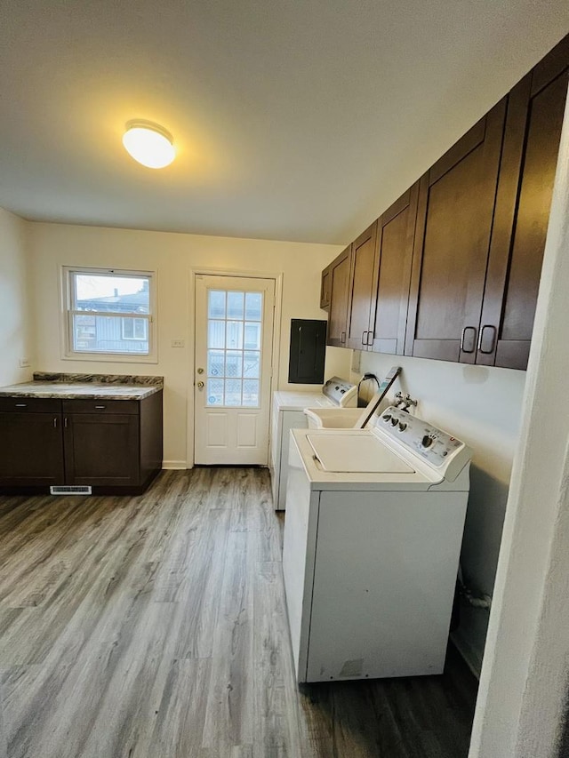 washroom with cabinets, separate washer and dryer, a healthy amount of sunlight, and light wood-type flooring