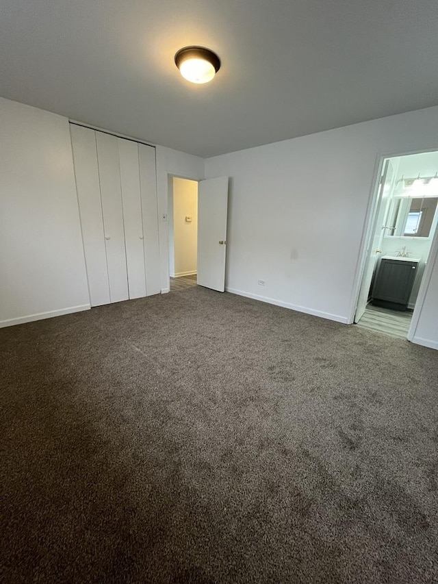 unfurnished bedroom with a closet, connected bathroom, and carpet