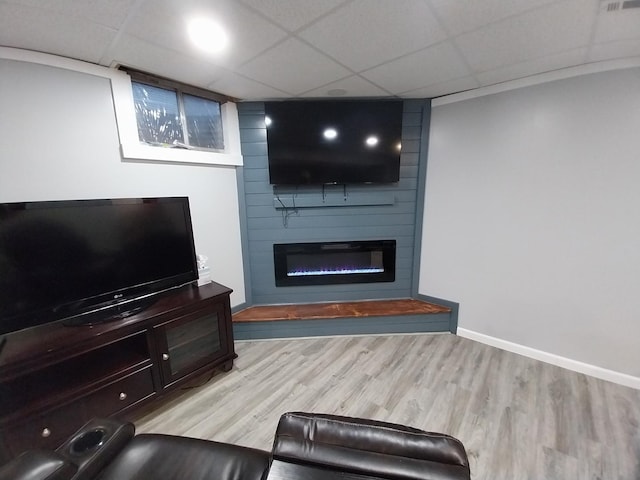 living room with light hardwood / wood-style flooring, a fireplace, and a paneled ceiling