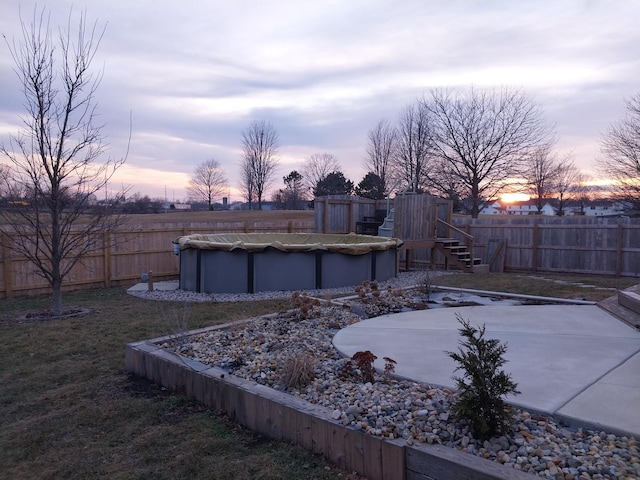 yard at dusk featuring a covered pool