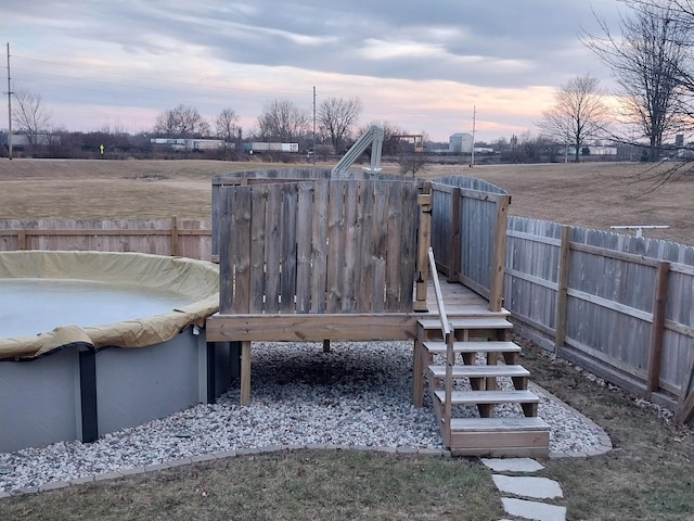 deck at dusk featuring a covered pool