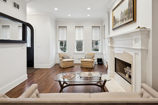 living room with crown molding, dark hardwood / wood-style flooring, and a high end fireplace