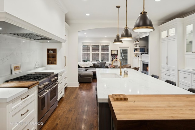 kitchen featuring white cabinetry, light stone countertops, custom range hood, decorative light fixtures, and range with two ovens