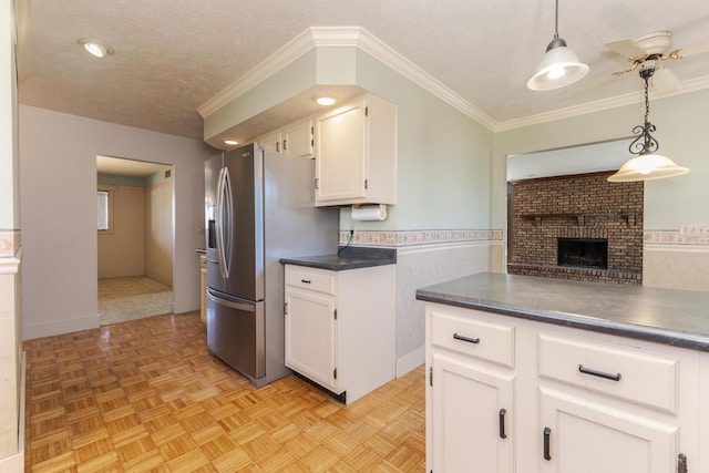 kitchen with a fireplace, dark countertops, white cabinetry, stainless steel refrigerator with ice dispenser, and pendant lighting