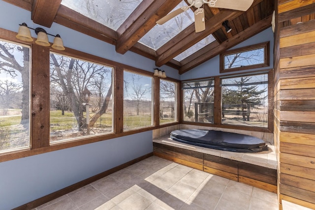 unfurnished sunroom featuring a wealth of natural light, lofted ceiling with skylight, baseboards, and tile patterned flooring