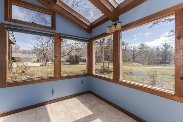 unfurnished sunroom with baseboards and lofted ceiling with skylight