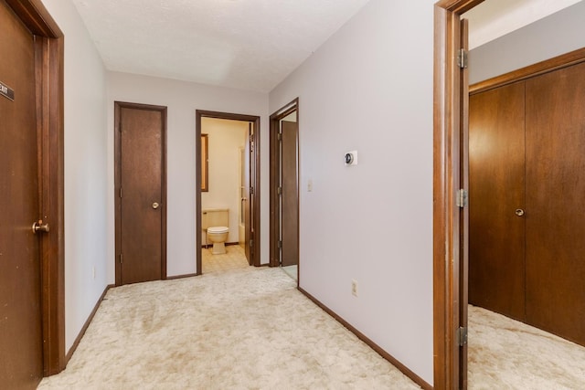 hall with baseboards and light carpet