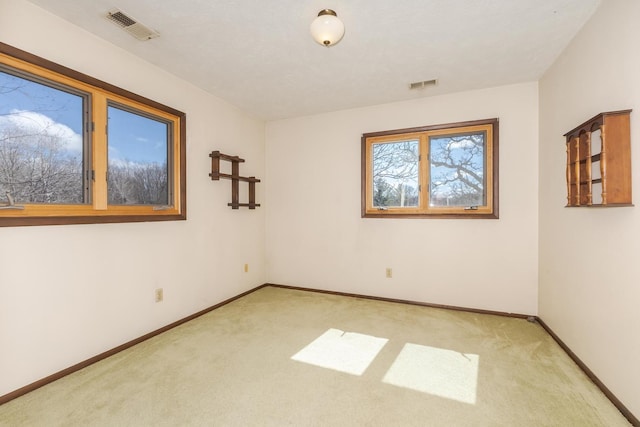 spare room featuring light carpet, baseboards, and visible vents