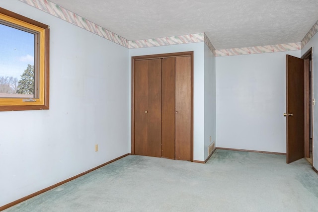 unfurnished bedroom with carpet floors, baseboards, a closet, and a textured ceiling