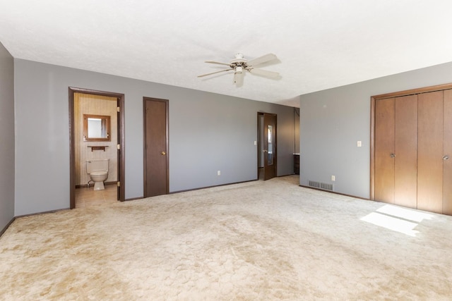 unfurnished bedroom featuring light colored carpet, visible vents, ceiling fan, and ensuite bathroom
