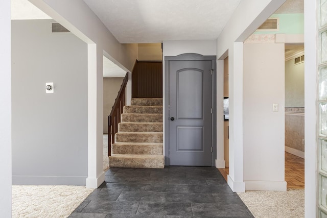 foyer entrance with baseboards, stairway, and visible vents