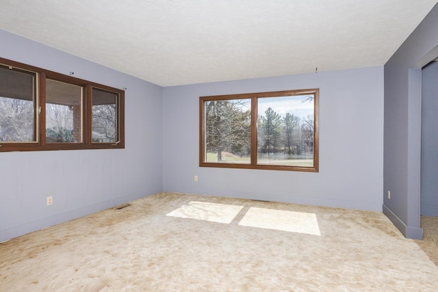 carpeted spare room with baseboards and a textured ceiling