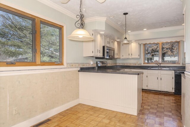 kitchen with a sink, a peninsula, visible vents, stainless steel appliances, and dark countertops