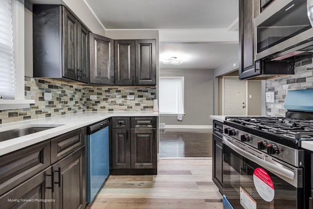 kitchen with stainless steel appliances, tasteful backsplash, dark brown cabinets, and light hardwood / wood-style flooring