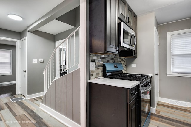 kitchen with gas stove, dark brown cabinets, and light wood-type flooring