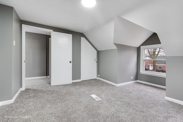 additional living space featuring lofted ceiling and light colored carpet