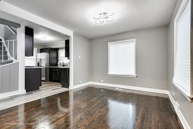 unfurnished living room featuring plenty of natural light, sink, and light hardwood / wood-style floors