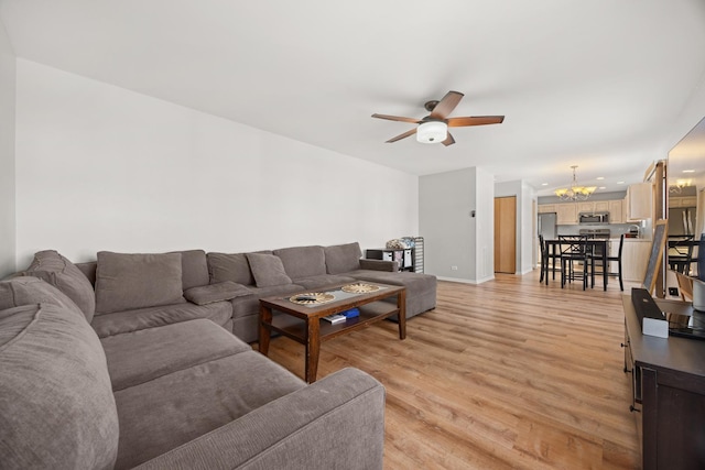 living room with ceiling fan with notable chandelier and light hardwood / wood-style floors