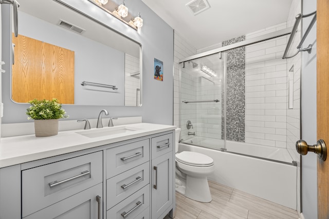 full bathroom with bath / shower combo with glass door, vanity, and toilet