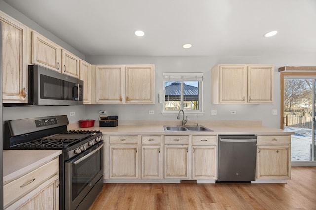 kitchen with stainless steel appliances, plenty of natural light, sink, and light hardwood / wood-style flooring