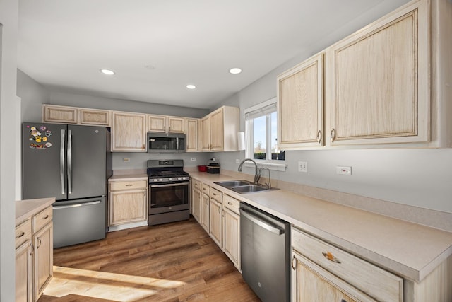 kitchen featuring appliances with stainless steel finishes, light brown cabinetry, sink, and light hardwood / wood-style flooring