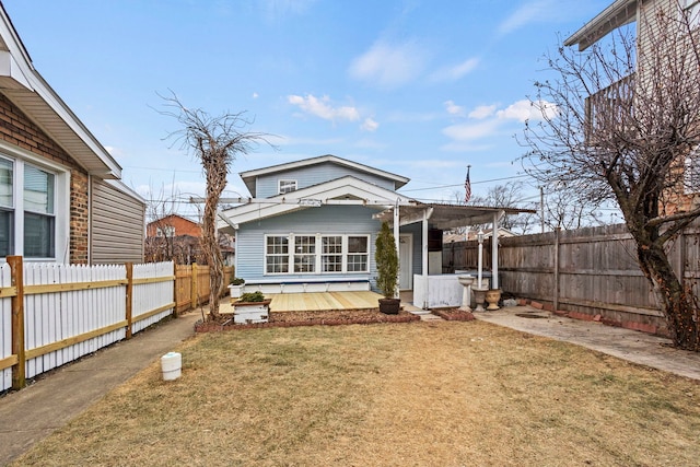 rear view of house with a carport, a fenced backyard, and a lawn