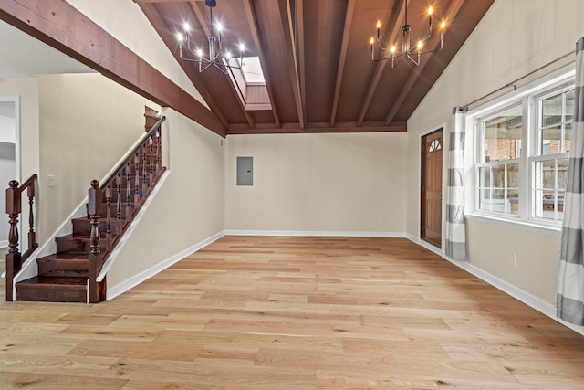 basement featuring a notable chandelier, electric panel, and light wood-type flooring