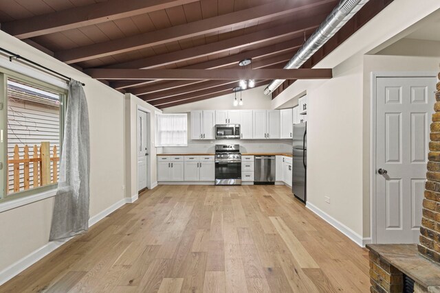 kitchen featuring appliances with stainless steel finishes, butcher block countertops, tasteful backsplash, white cabinetry, and hanging light fixtures