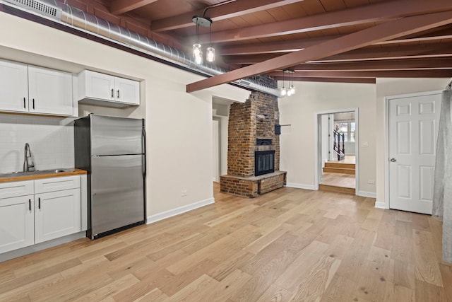 kitchen featuring sink, white cabinetry, decorative light fixtures, stainless steel fridge, and decorative backsplash