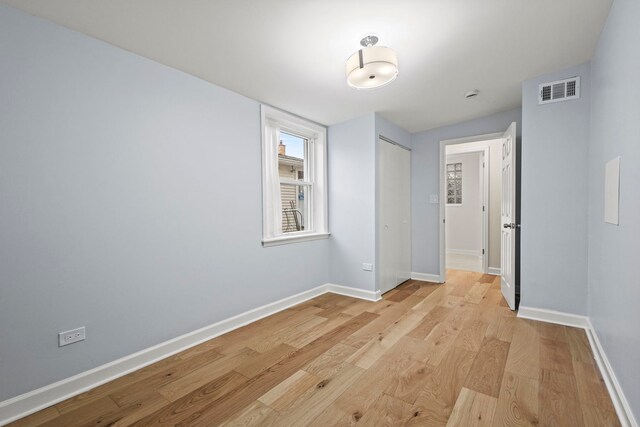 spare room with lofted ceiling with skylight and light wood-type flooring