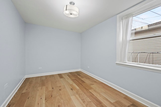 spare room featuring light wood-type flooring and baseboards