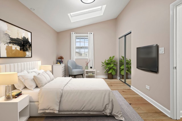 bedroom featuring vaulted ceiling with skylight, baseboards, light wood finished floors, and radiator heating unit