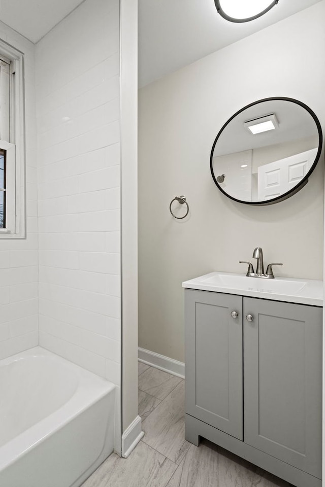 full bathroom with marble finish floor, tub / shower combination, vanity, and baseboards