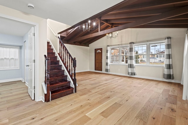 entryway featuring light wood finished floors, a notable chandelier, stairway, and a wealth of natural light