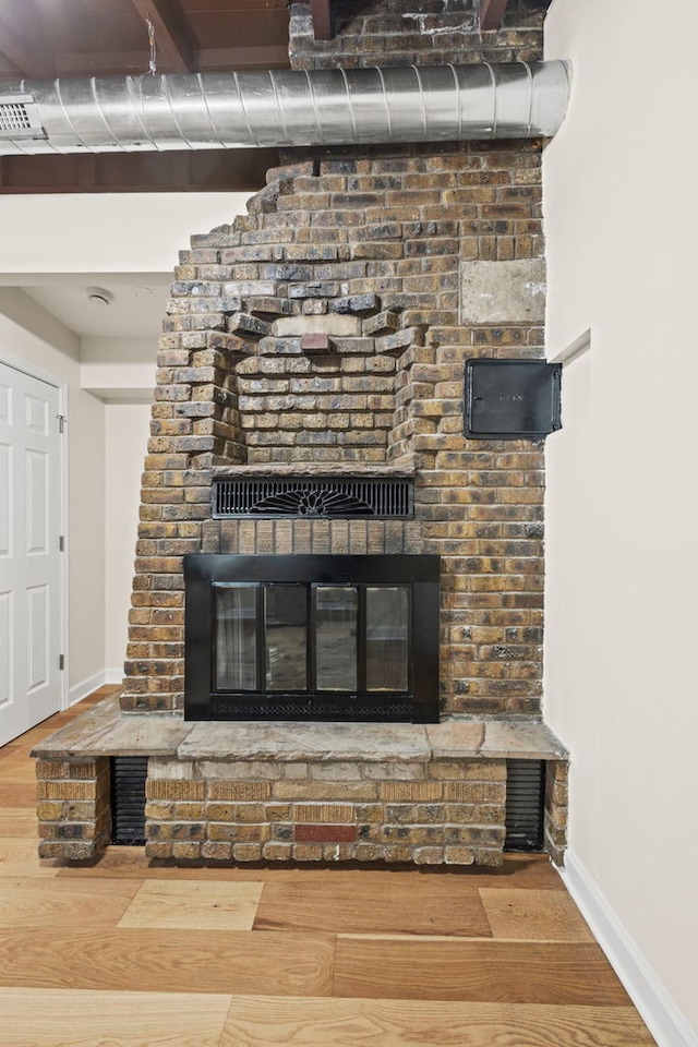 interior details featuring visible vents, a fireplace, baseboards, and wood finished floors