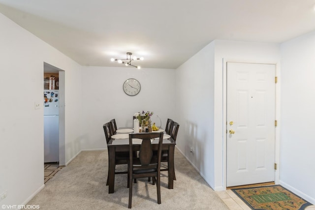 dining space featuring light colored carpet and a notable chandelier