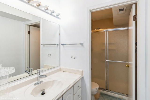 bathroom featuring a shower with door, vanity, and toilet