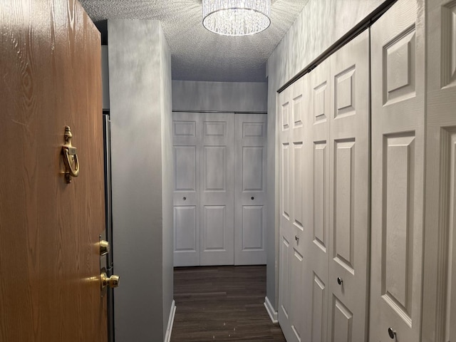 hall with dark wood-type flooring and a textured ceiling