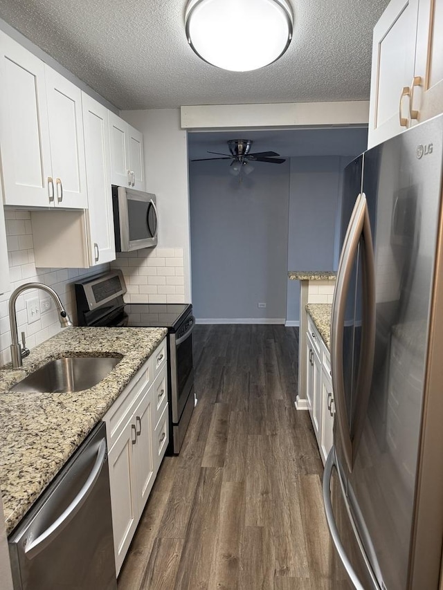 kitchen with light stone countertops, white cabinetry, appliances with stainless steel finishes, and sink