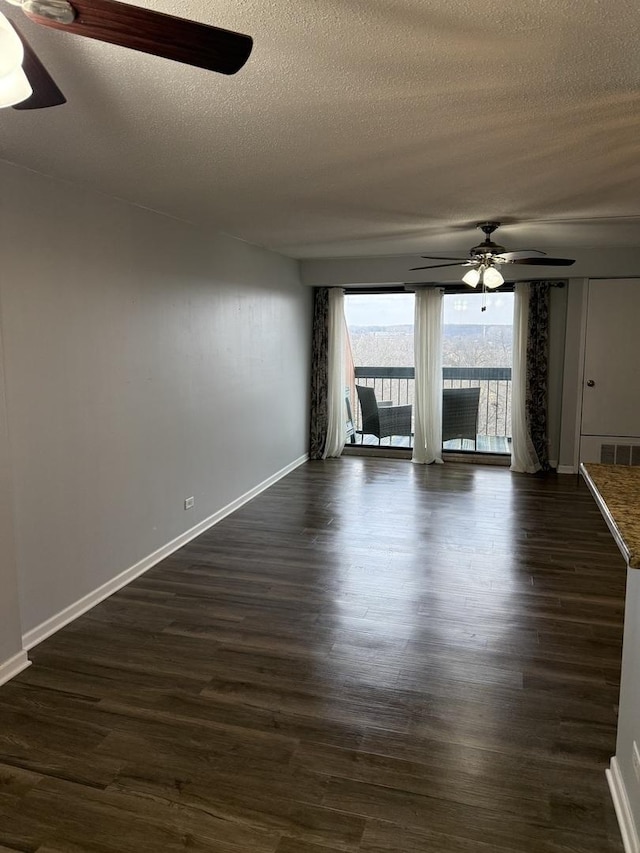 empty room with dark hardwood / wood-style floors, a textured ceiling, and ceiling fan