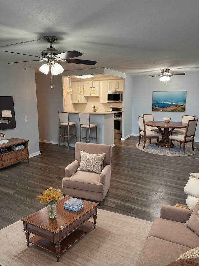 living room with dark wood-type flooring and ceiling fan