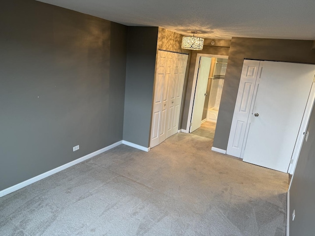 unfurnished bedroom with multiple closets, carpet flooring, and a textured ceiling